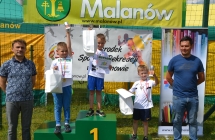 Troje małych chłopców z pucharami w towarzystwie dwóch mężczyzn 