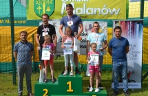 Trzy dziewczynki na podium wraz z rodzicami. Obok dwoje mężczyzn 