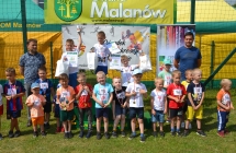 Kilkunastu zadowolonych chłopczyków. Troje na podium. Obok dwoje mężczyzn 