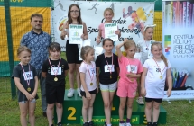 Trzy dziewczynki na podium. Przed nimi kilka dziewczynek z medalami i mężczyzna 