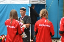 Trzy dziewczyny w jednakowych strojach oraz mężczyzna, któremu wręczany jest medal za uczestnictwo w biegach 