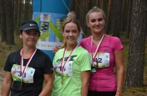 Trzy kobiety usmiechające się do fotografii, na szyjach mają medale 