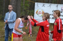 Dziewczynka nakładająca na szyję uczestniczki biegów medal 