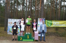 Trzy kobiety na podium  z nagrodami za bieg, obok nich stoi dwoje mężczyzn 