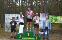 Pięcioro mężczyzn, trójka stoi na podium i trzyma nagrody 