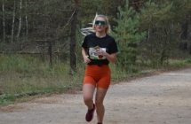 Młoda kobieta w sportowym stroju biegnie leśną ścieżką 