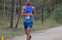 Mężczyzna w sportowym stroju biegnący przez ścieżkę w lesie 