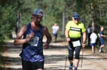 Dwoje mężczyzn podczas zawodów - jeden biegnie, drugi idzie w marszu nordic walking 