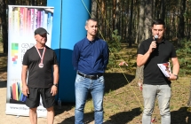 Troje mężczyzn. Jeden mówi do mikrofonu 